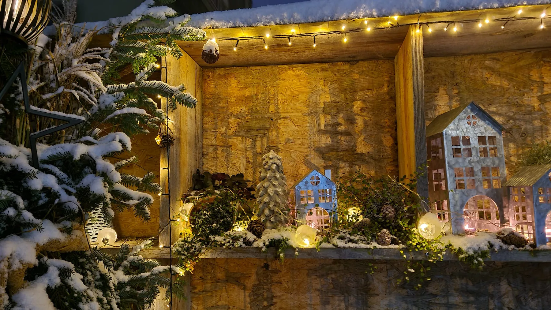 Winterliches Blumenfenster mit Lichtern und natürlichen Materialien