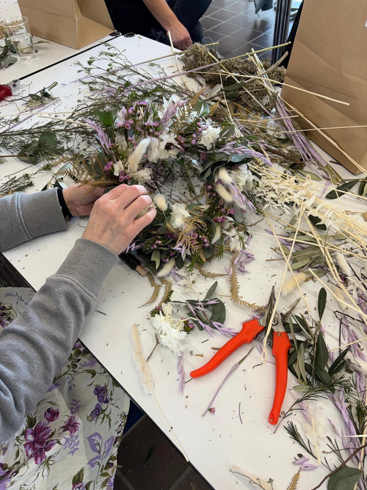 Hände beim Gestalten eines Adventsgestecks mit Naturmaterialien