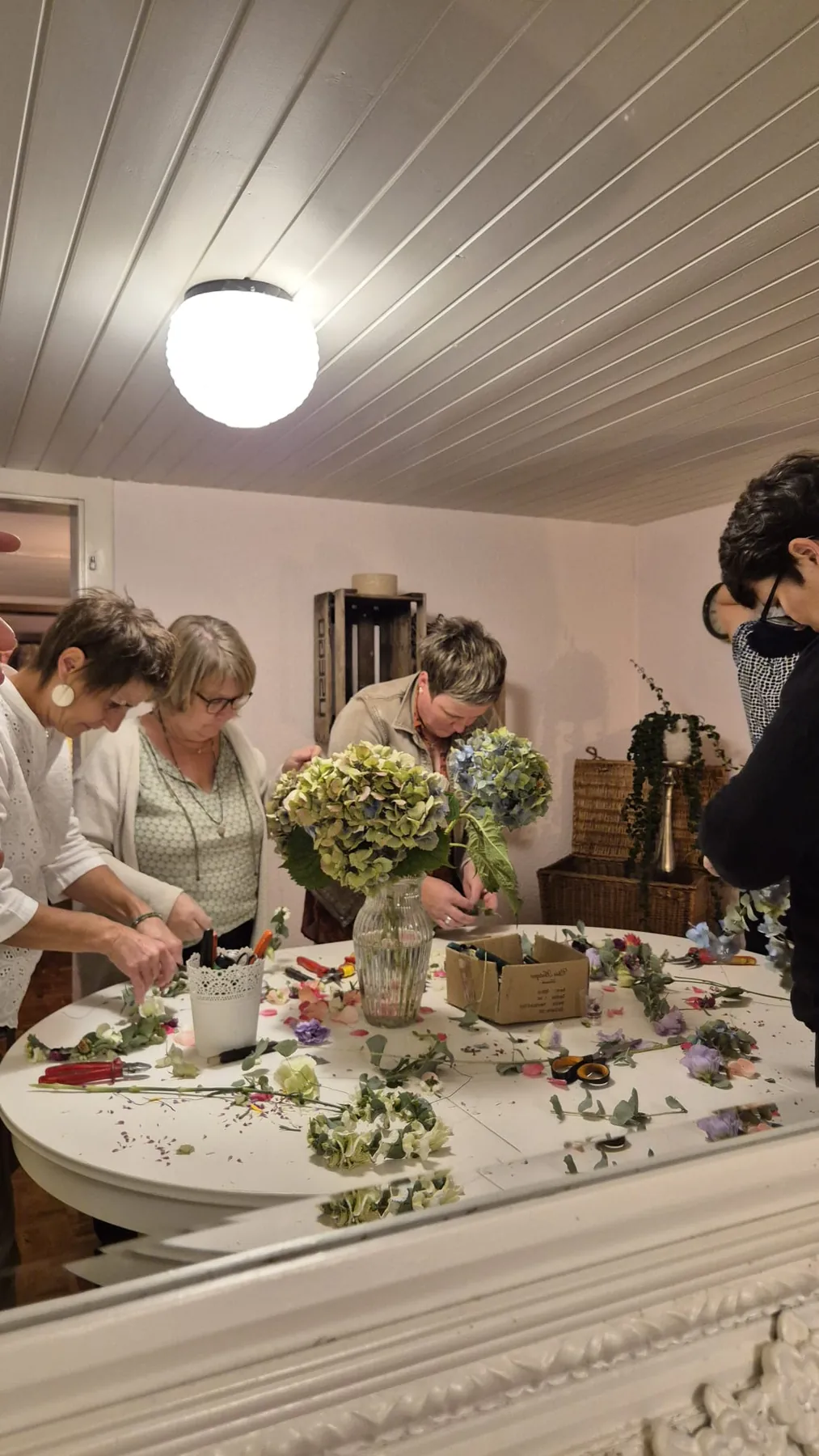 Teilnehmerinnen gestalten floristische Werkstücke am Tisch