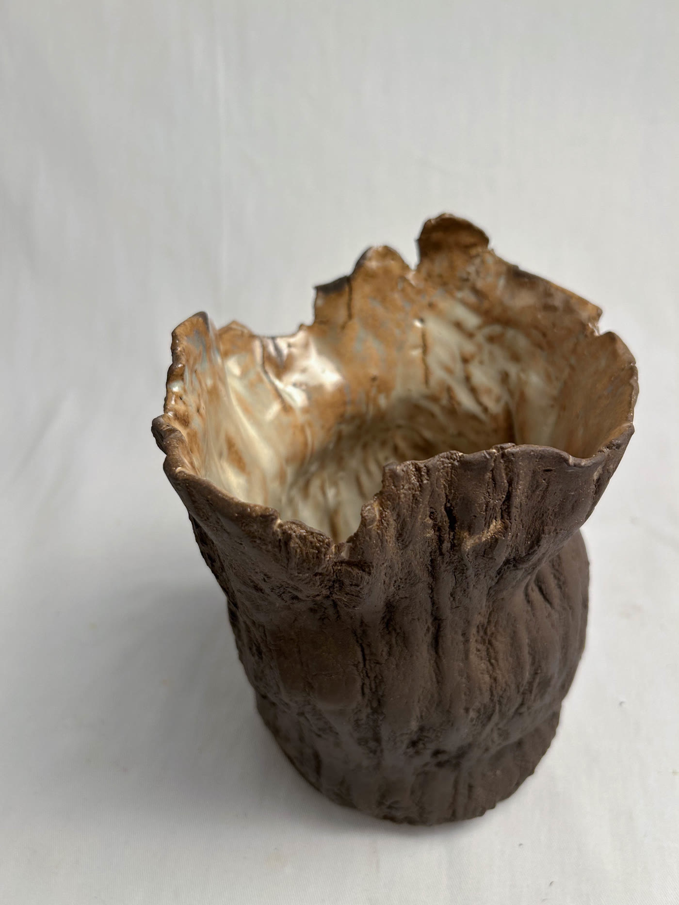 Hand-built ceramic vessel with a torn rim, rough dark exterior and pale glazed interior, by Consuelo Becerra