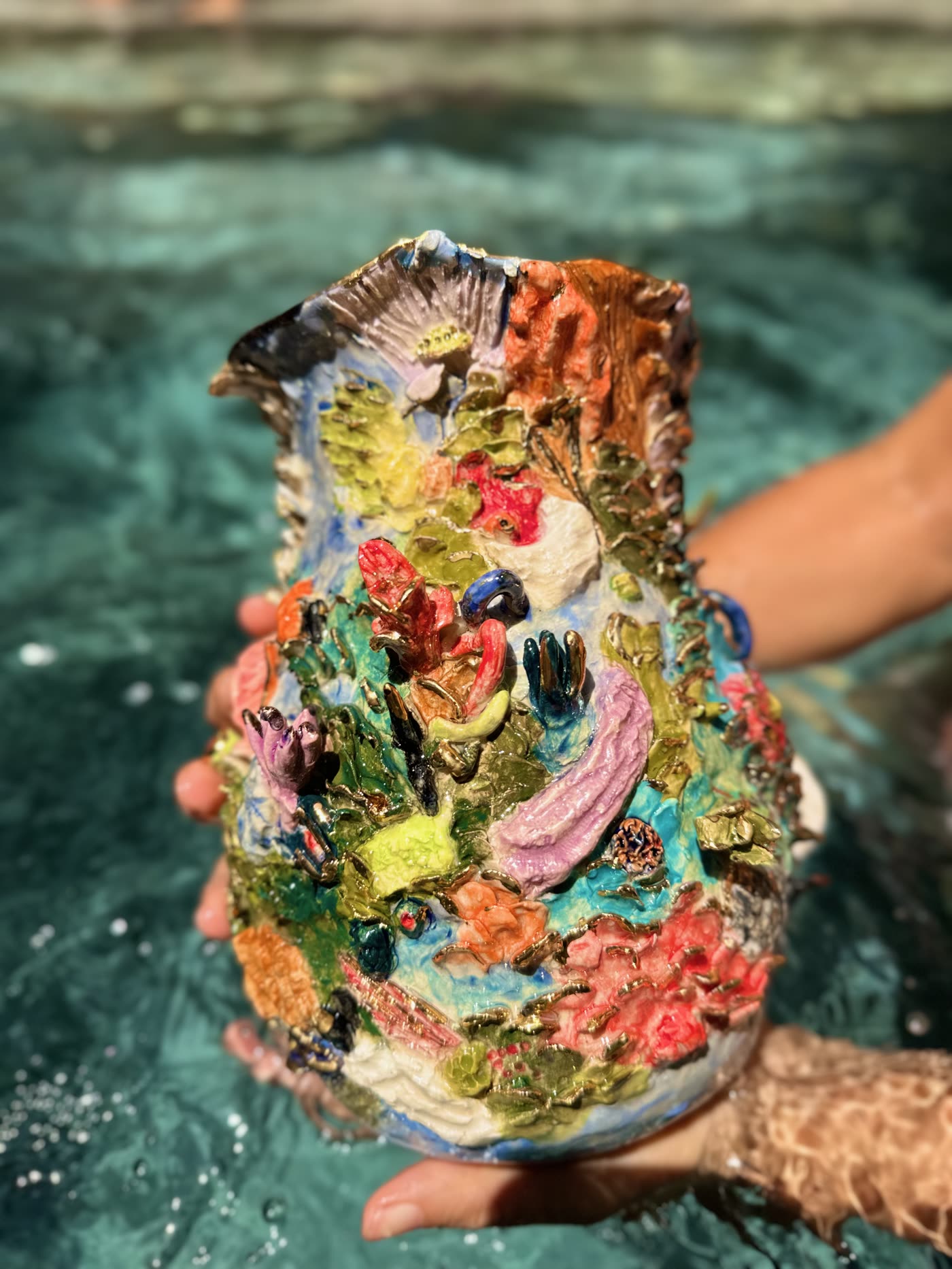 Coral reef ceramic vessel by Consuelo Becerra in sunlight above a pool, showing coral and shell relief, view 5 of 5