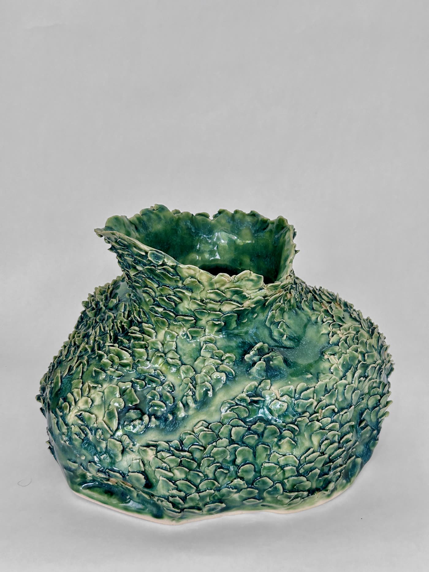 Scaled green ceramic vessel by Consuelo Becerra from a lower angle, showing the rounded body, view 5 of 6
