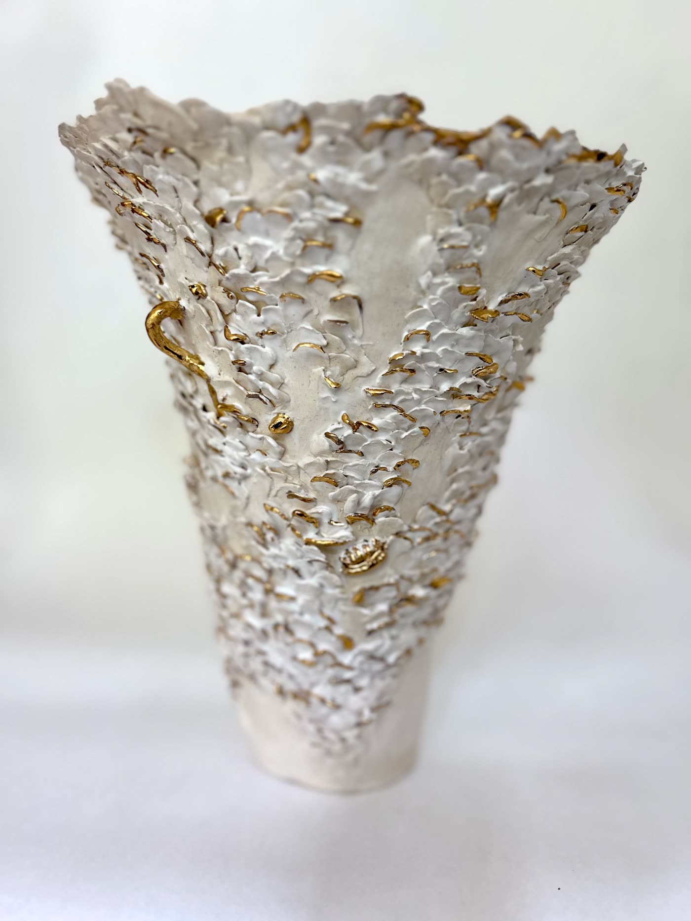 The white and gold flared vessel by Consuelo Becerra from the side, showing how the form widens from the foot, view 3 of 8