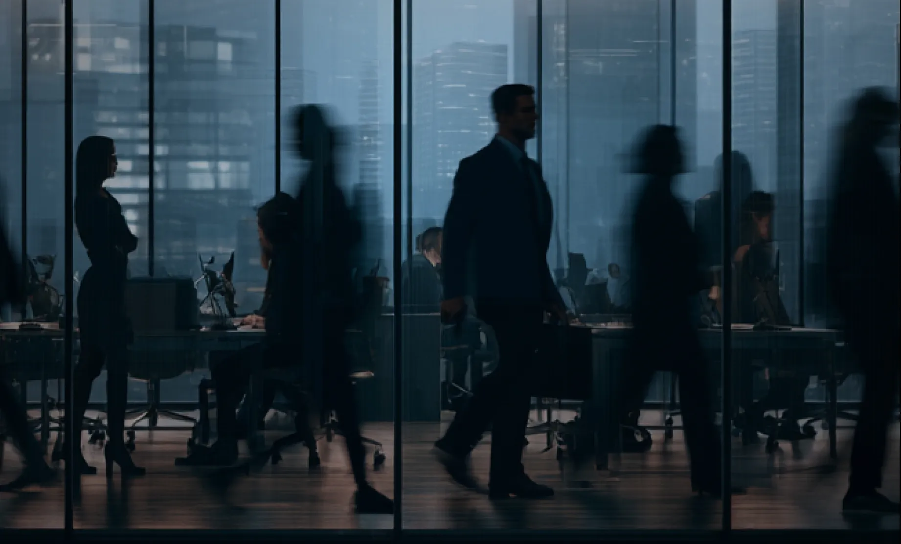 Silhouettes of business people walking and standing inside a modern glass office with city buildings visible through the windows.