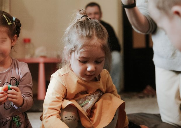A stock photo of a little girl in orange playing on the ground