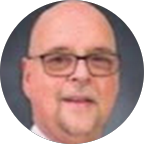 Portrait of a bald middle-aged man with glasses, a trimmed beard, and a slight smile, against a neutral background.