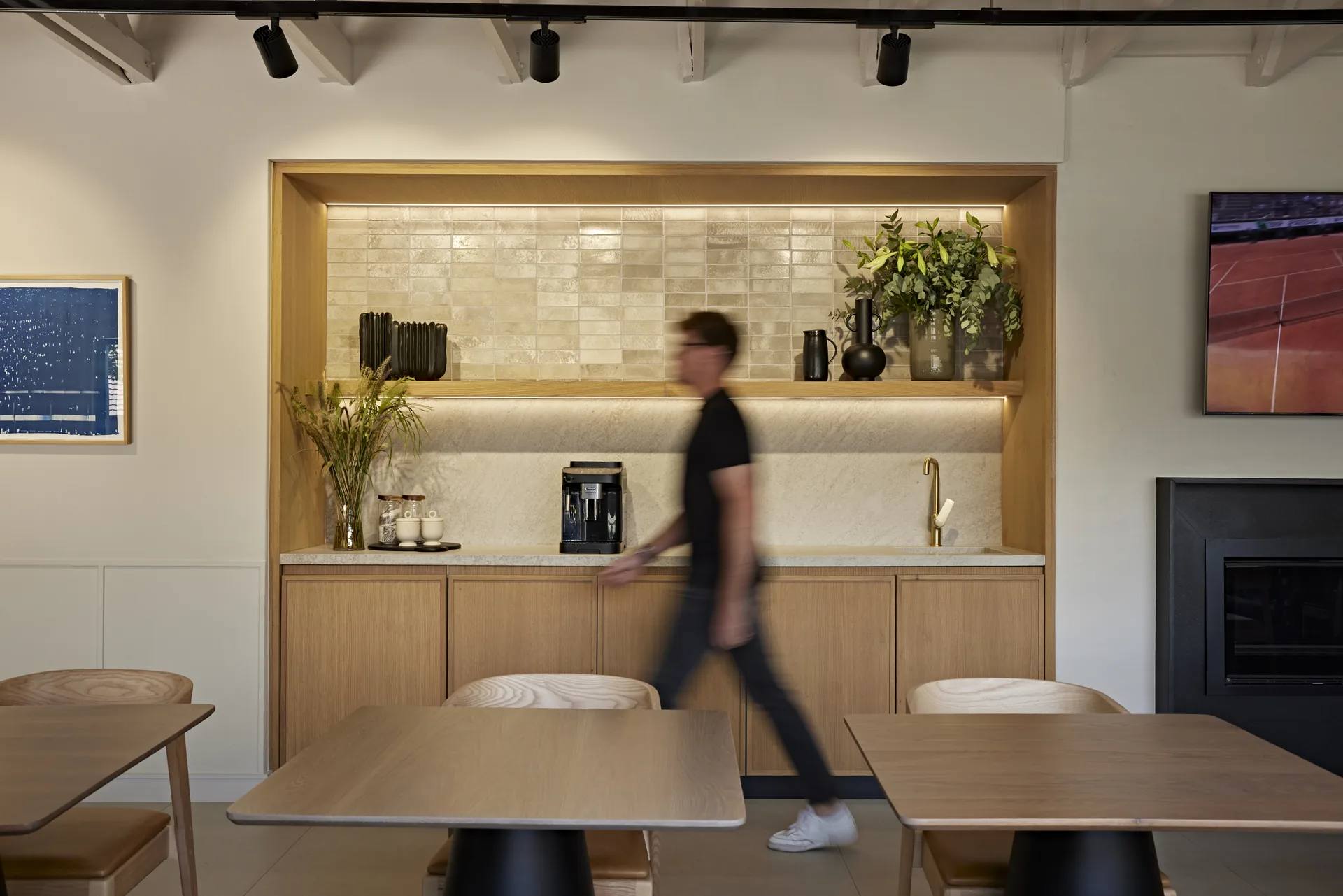 A Design Partnership team member walking through the studio past the material library and meeting areas.