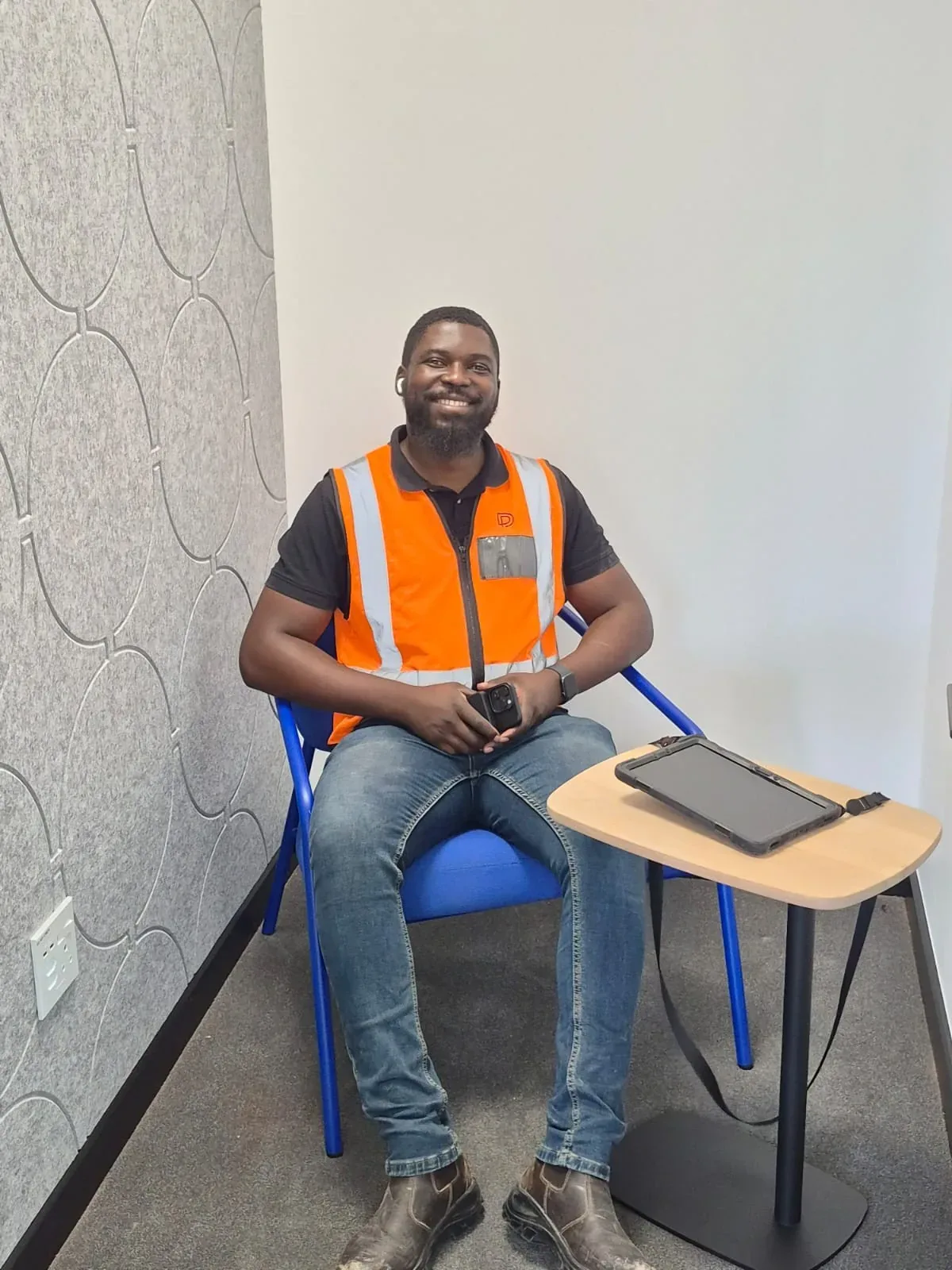 A Design Partnership site supervisor in branded safety wear reviewing drawings on a live project.