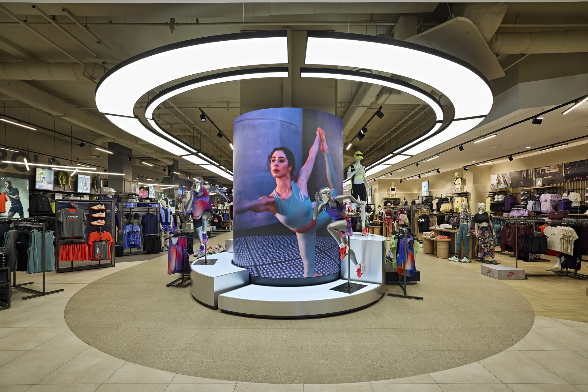 Retail store interior with a circular LED display ring, curated merchandising and warm feature lighting, designed and built by Design Partnership.