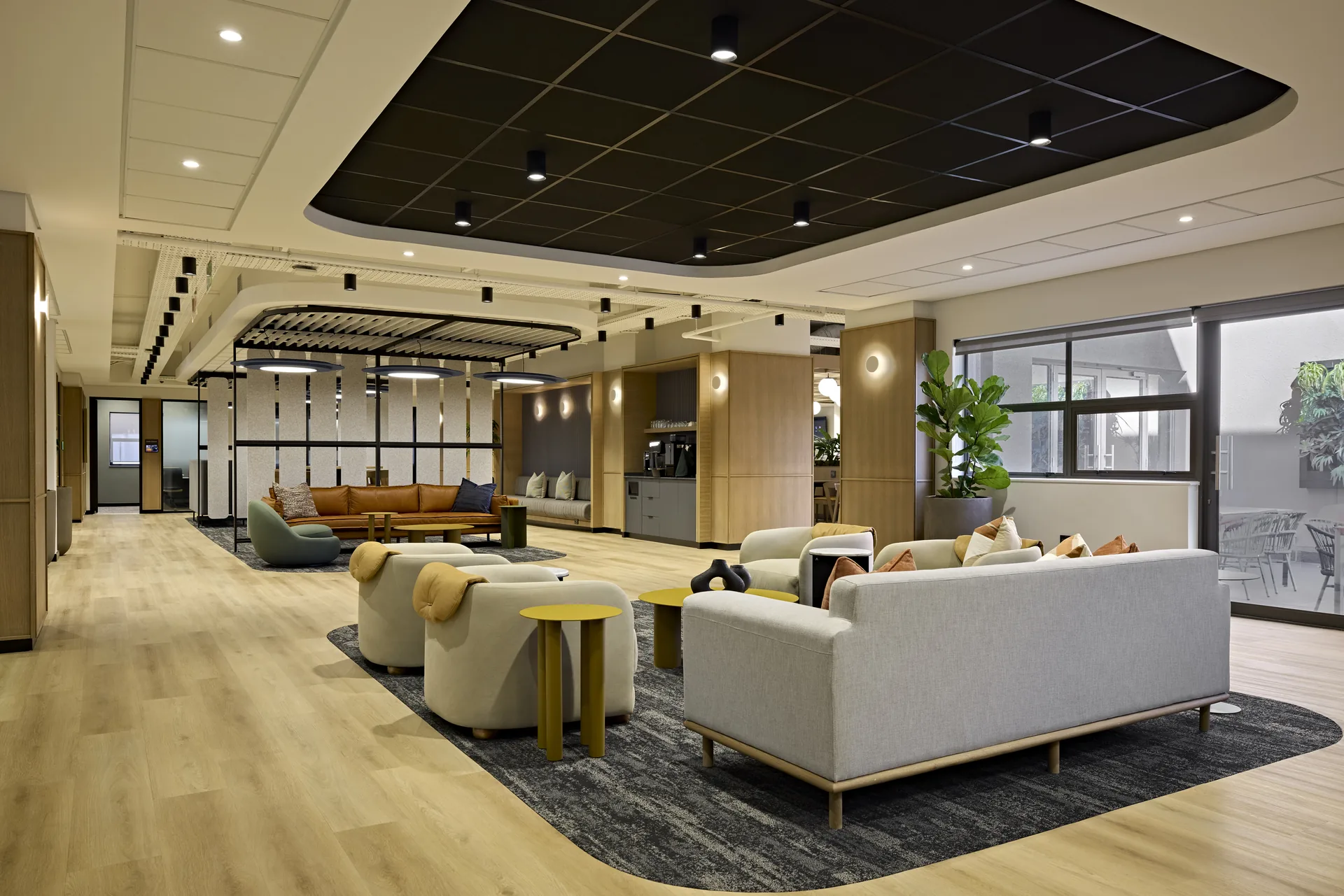 Workplace breakout lounge with upholstered armchairs, brass side tables and a timber slat feature wall, designed and built by Design Partnership.