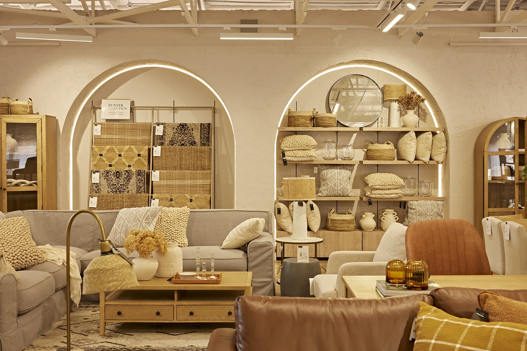 Coricraft showroom with arched display niches and layered lighting, designed by Design Partnership.