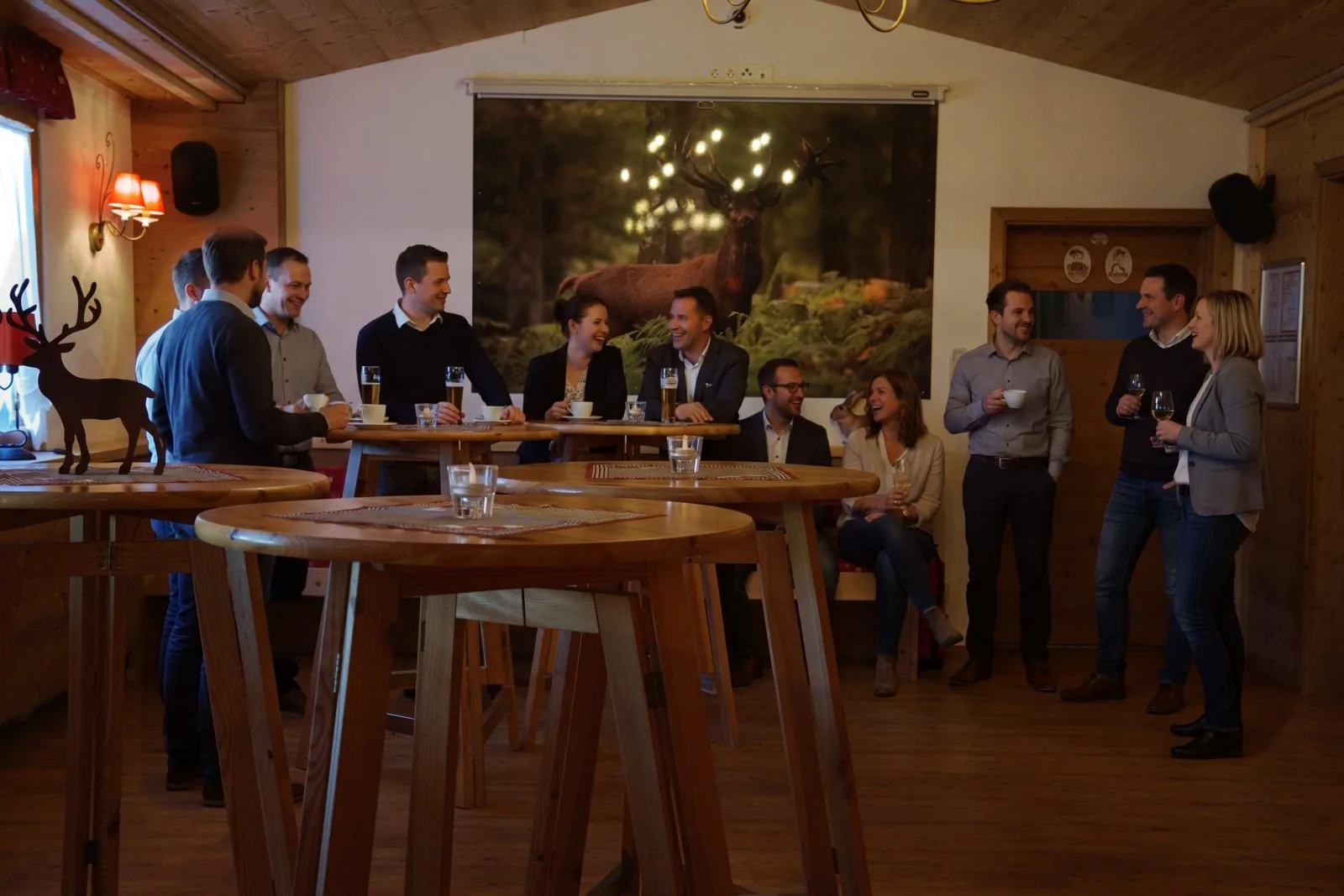 Freunde in rustikalem Holzraum sitzen an Tischen, trinken Kaffee und lachen zusammen.
