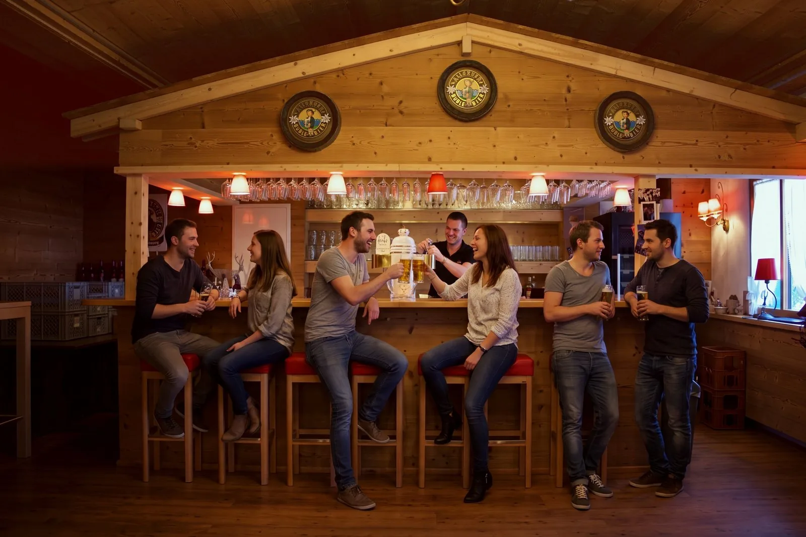 Freunde feiern an der Bar der Hirschalm und stoßen mit Bier an