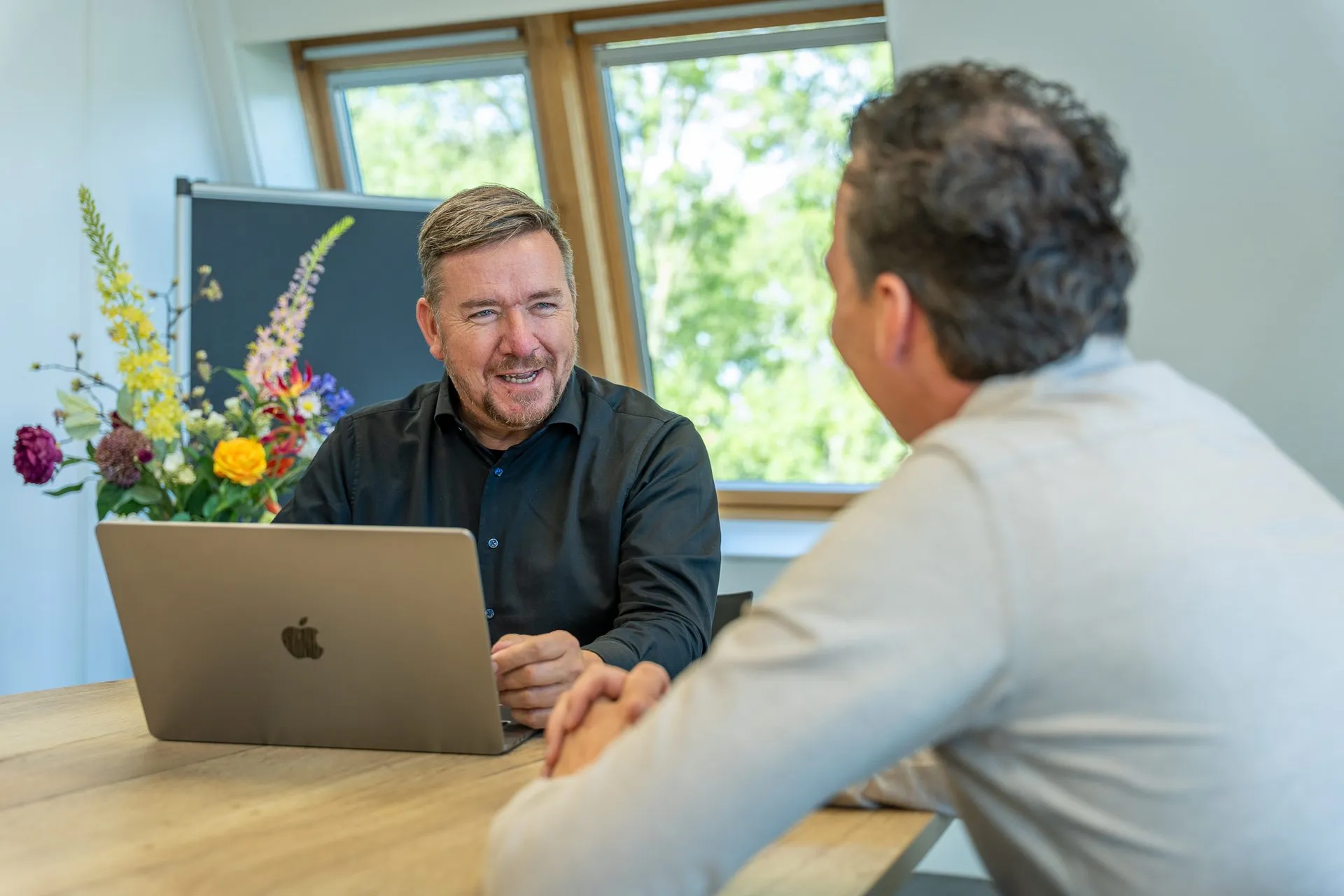 Kennismakingsgesprek op kantoor Arbeidsmakelaar voert een kennismakingsgesprek aan tafel met laptop op kantoor