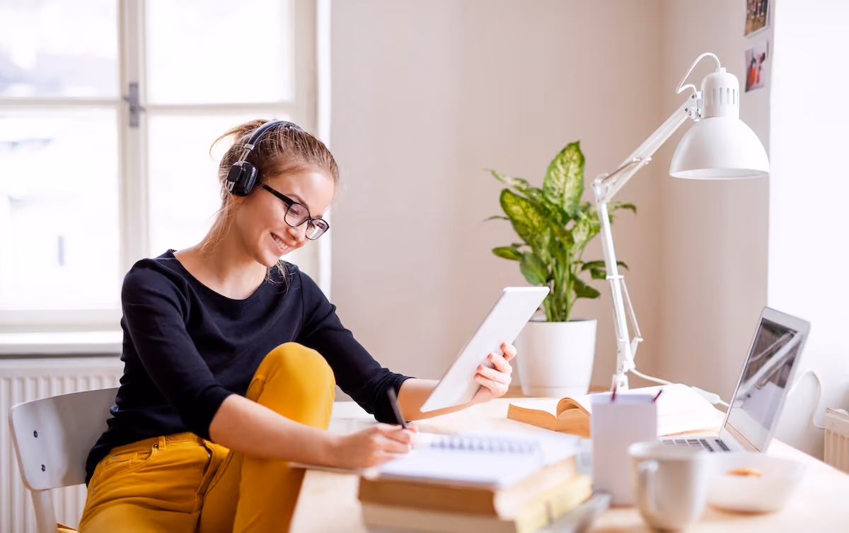 Young woman with glasses studying wth ipad and lap top