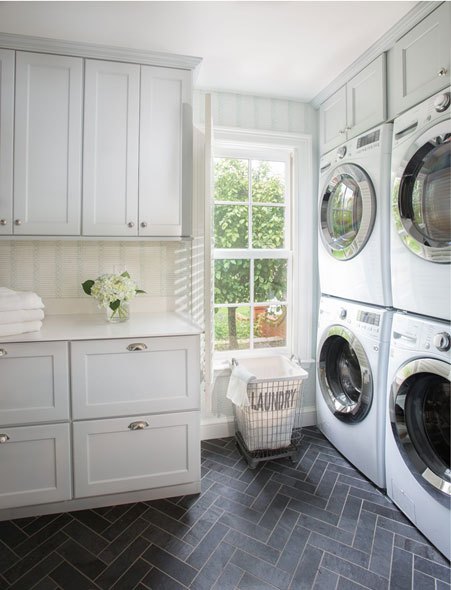 Modern laundry room with white cabinets, sink, and stacked washing machines