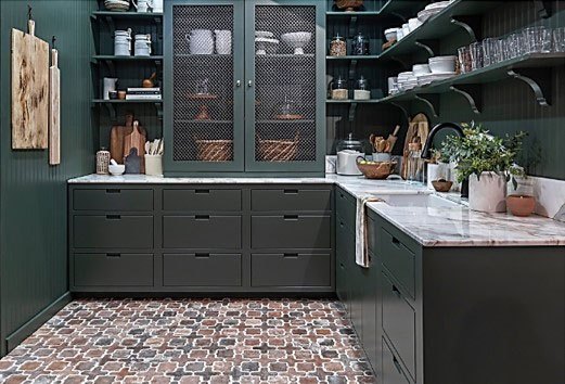 Modern kitchen with dark green cabinetry, marble countertops, patterned tile flooring, and open shelving.