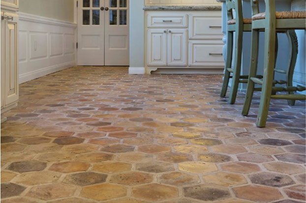 Spacious interior room with terracotta geometric tile flooring, white cabinetry, and vintage furniture.