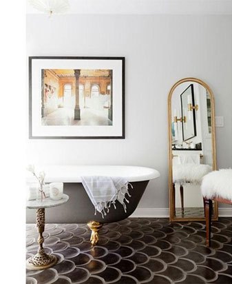 Luxurious bathroom with freestanding white bathtub, framed architectural print, and decorative gold mirror.