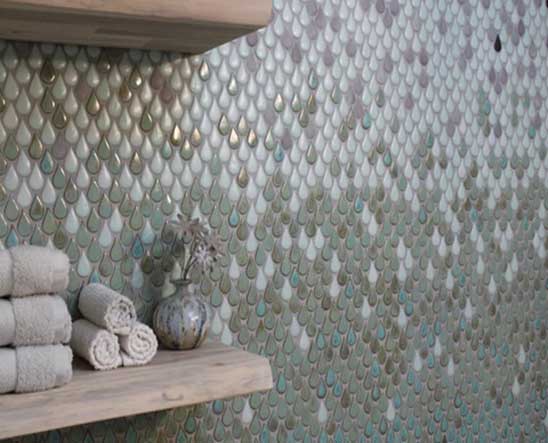 Bathroom with iridescent teardrop tile walls, rolled towels, and decorative objects on shelf