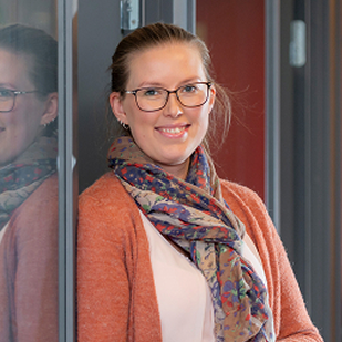 Portrett av smilende medarbeider i en kontorgang