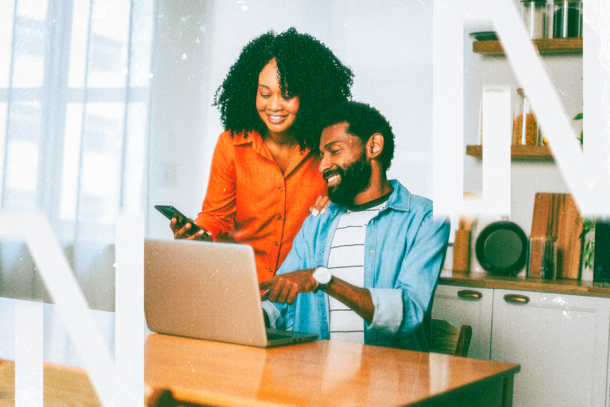 Two people reviewing a laptop together at a kitchen table.
