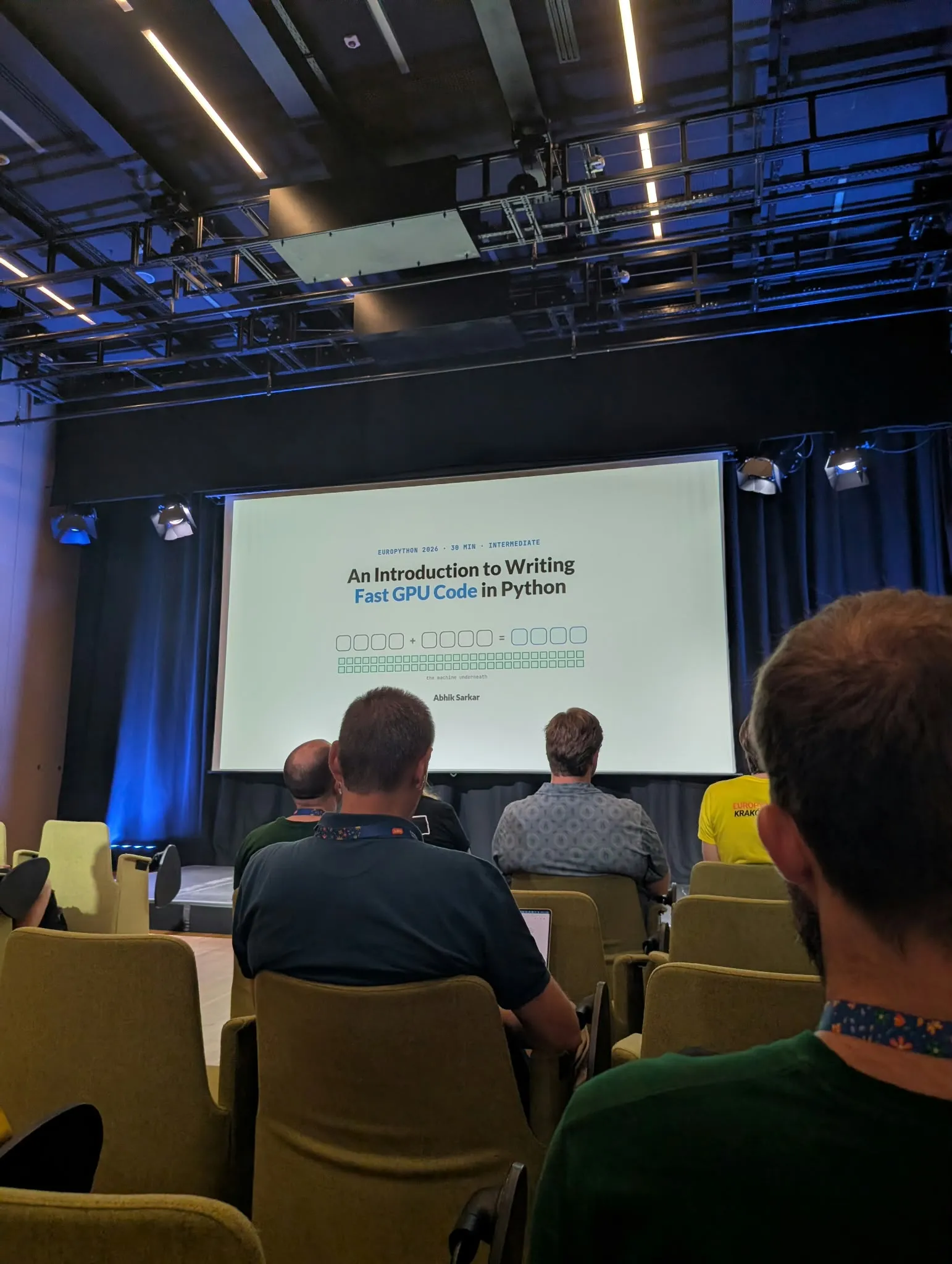 Audience seated in a conference room facing a presentation screen displaying a slide titled 'An Introduction to Writing Fast GPU Code in Python' by Abhik Sarkar at EuroPython 2026.
