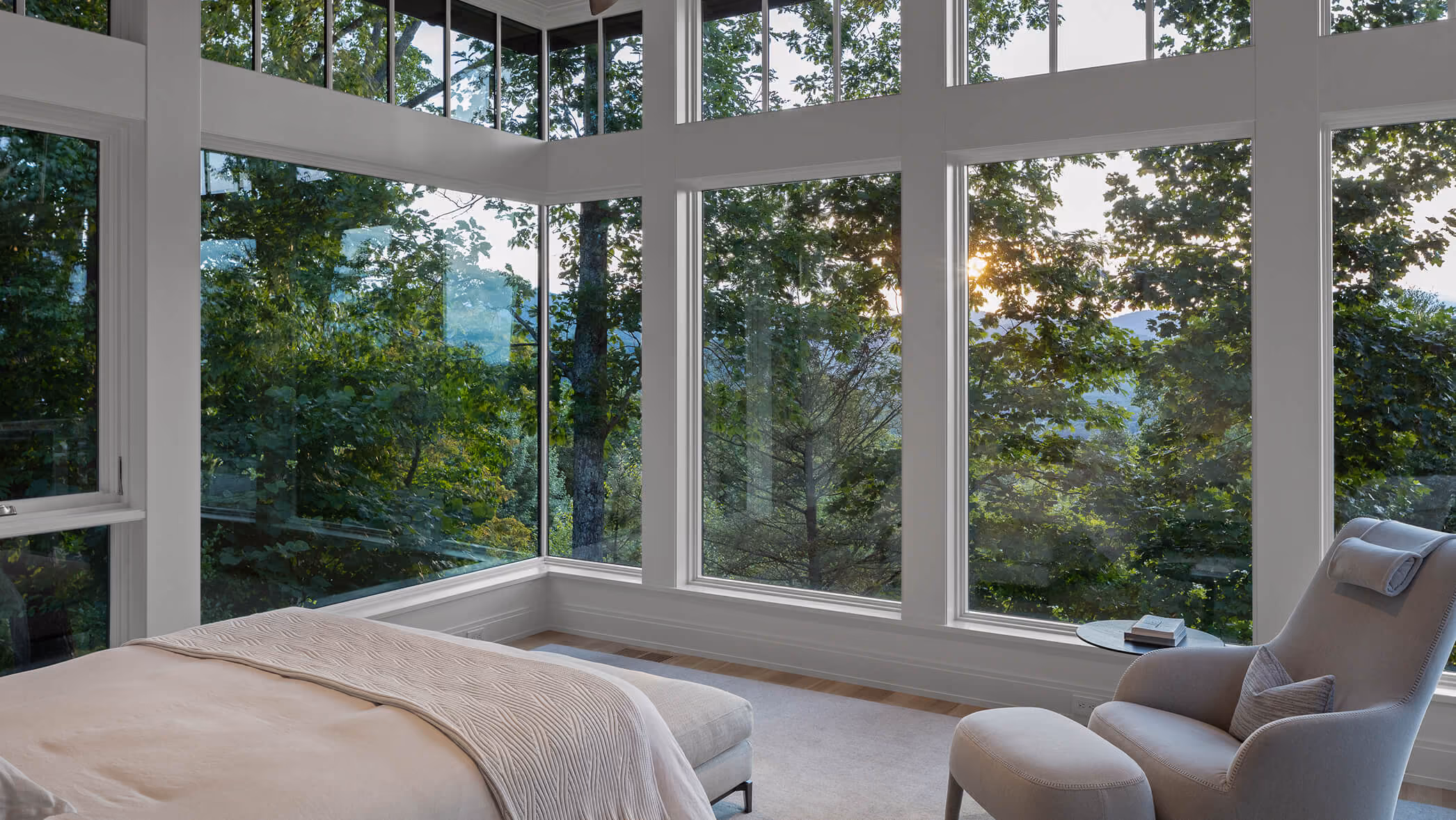 Large estate with stone house, pool, and tennis court surrounded by dense forest and hills.