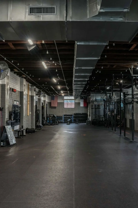 Spacious CrossFit LoSo gym interior with squat racks, free weights, rowing machines, and climbing ropes.
