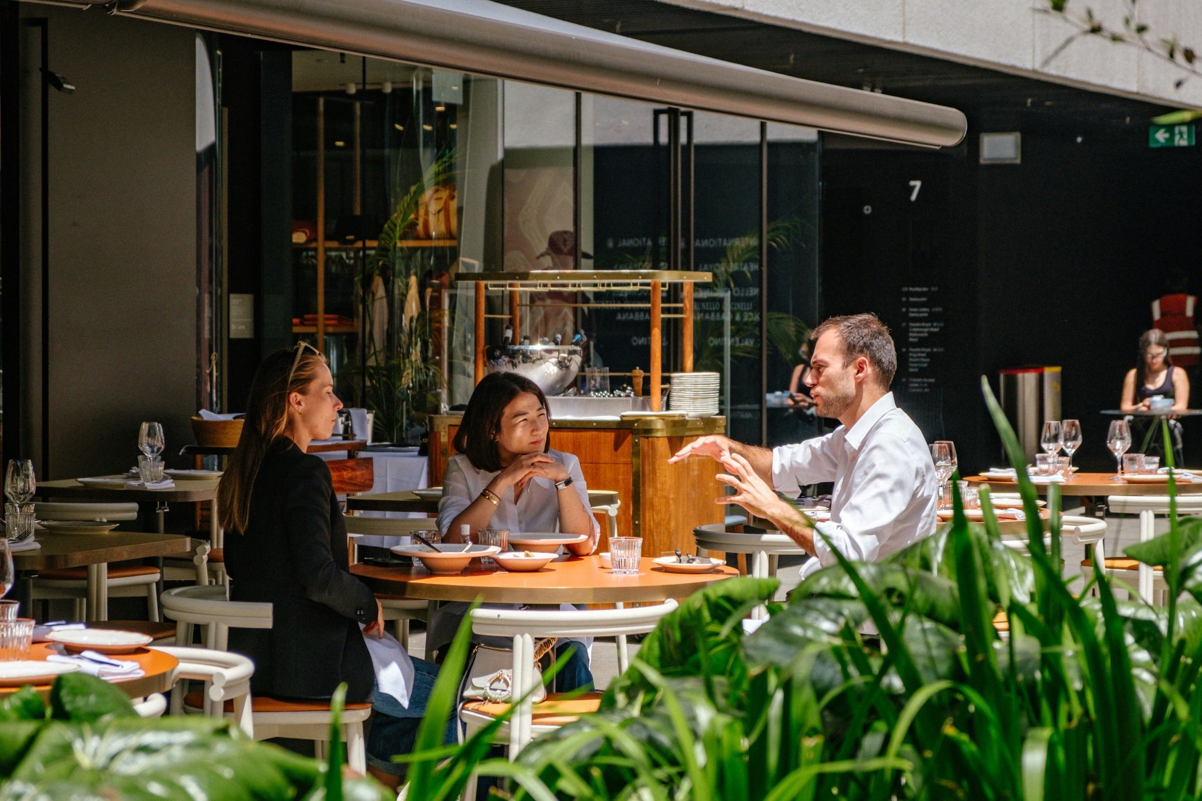 Three colleagues in conversation over lunch at an outdoor table