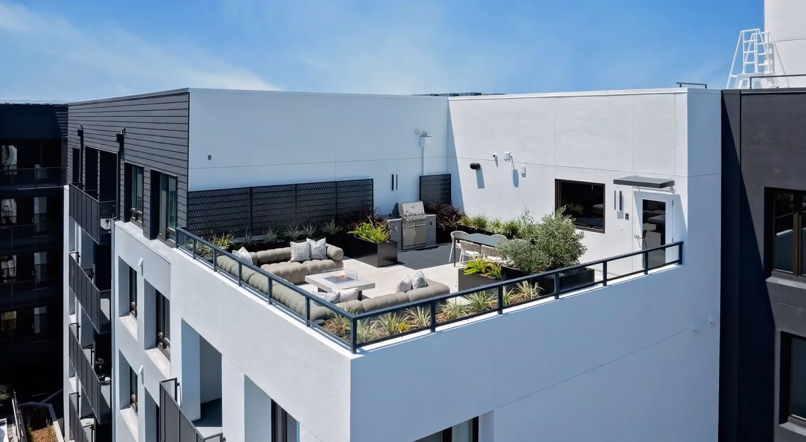 Aerial view of rooftop lounge area with grilling station and fire pit