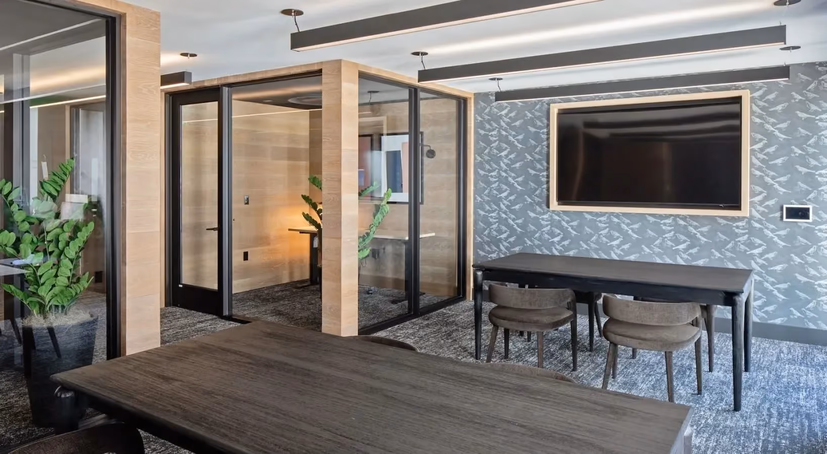 Community workspace with mounted TV and view of private offices