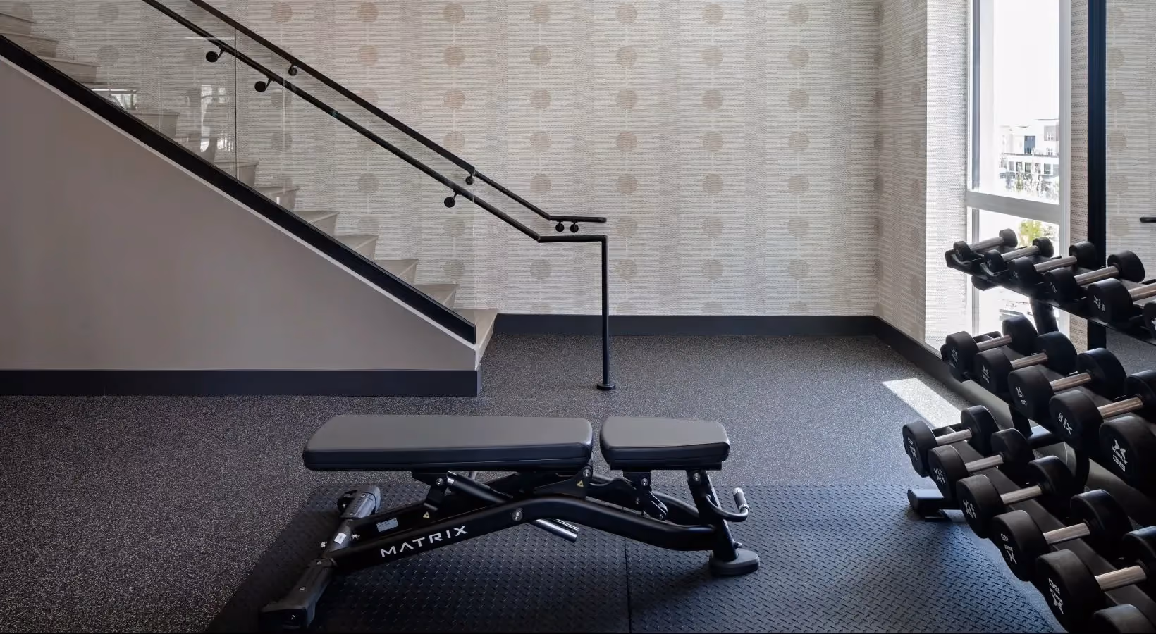 Fitness center with free weights, weight bench, and stairs to second level