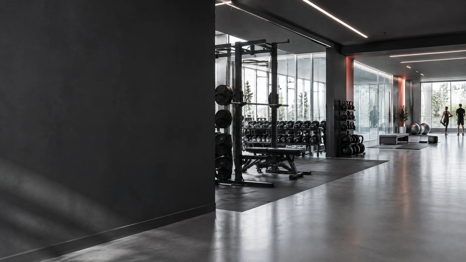 Interior of a modern gym with a squat rack, racked dumbbells and polished concrete floors