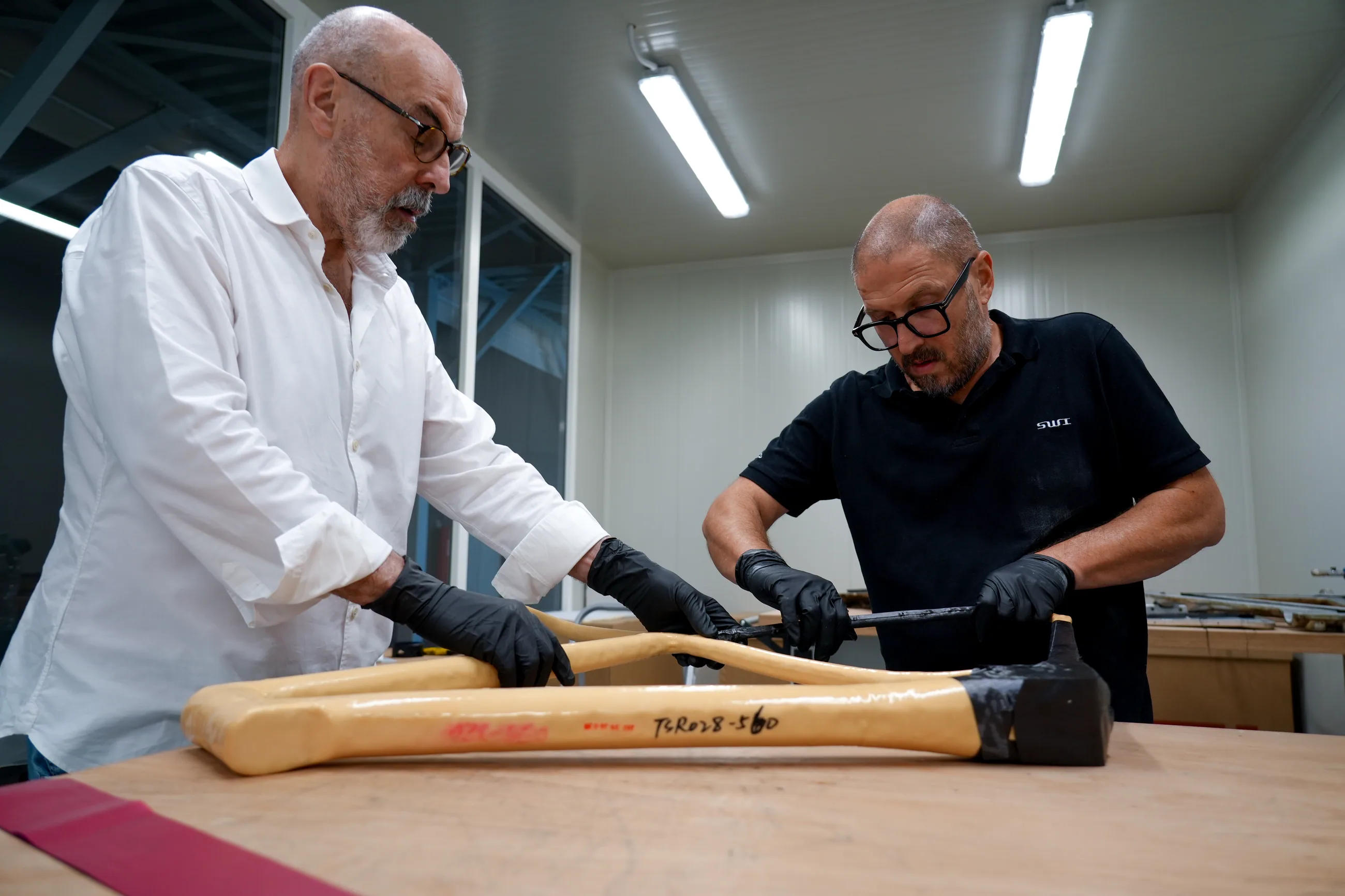 Two SWI craftsmen laying carbon at the bench in the Villafranca Padovana workshop