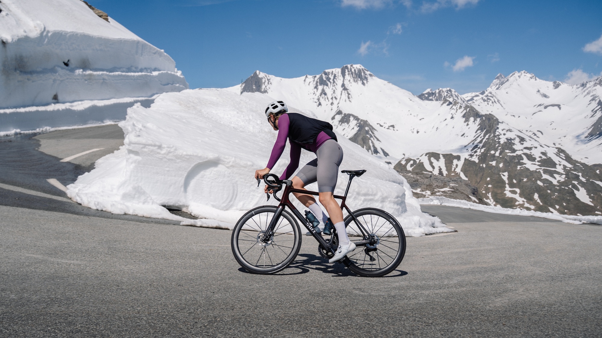 A rider on a snow-lined alpine pass on a SWI