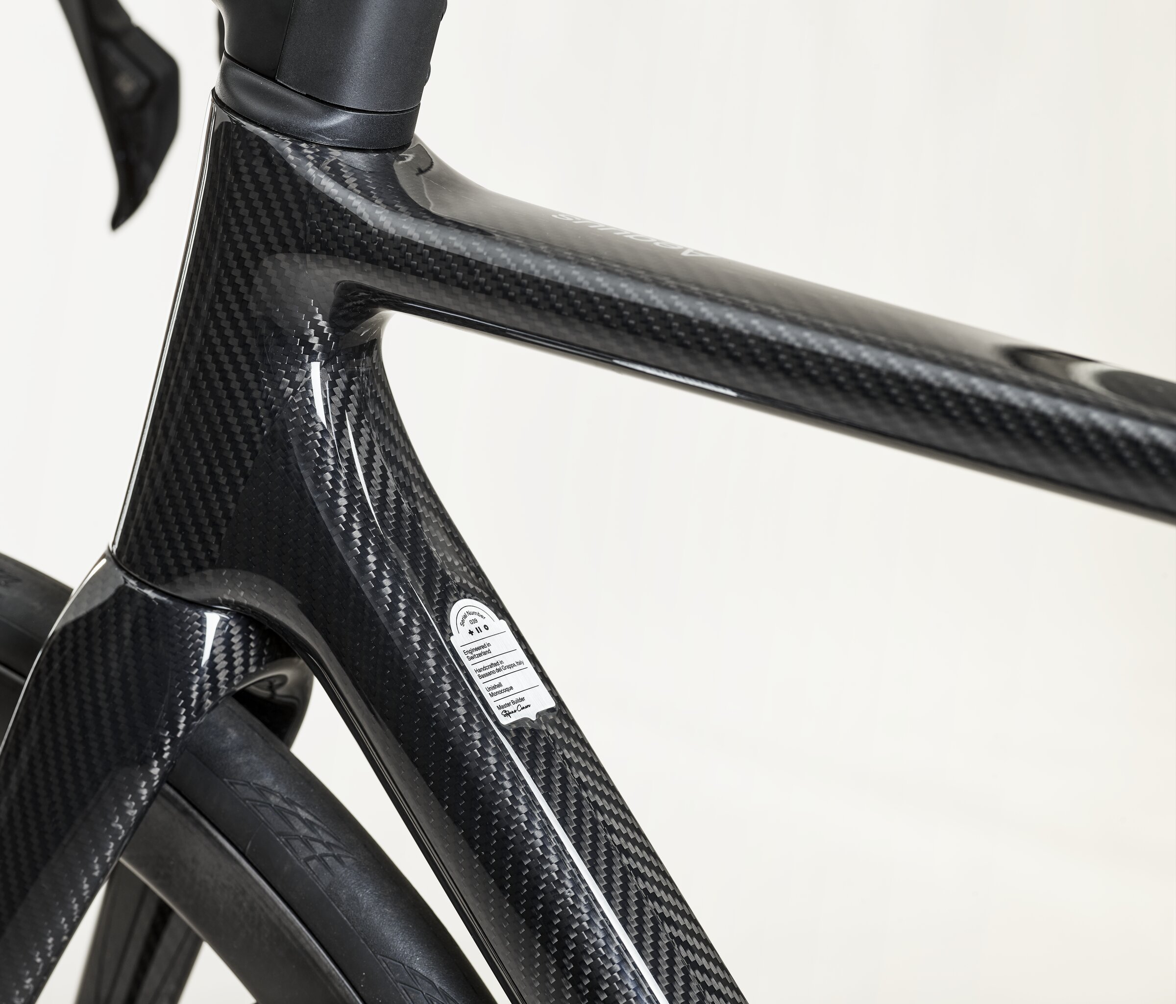 Close detail of the SWI Aequus head tube and down tube junction in gloss, the 3K Herringbone weave clearly visible through the clearcoat