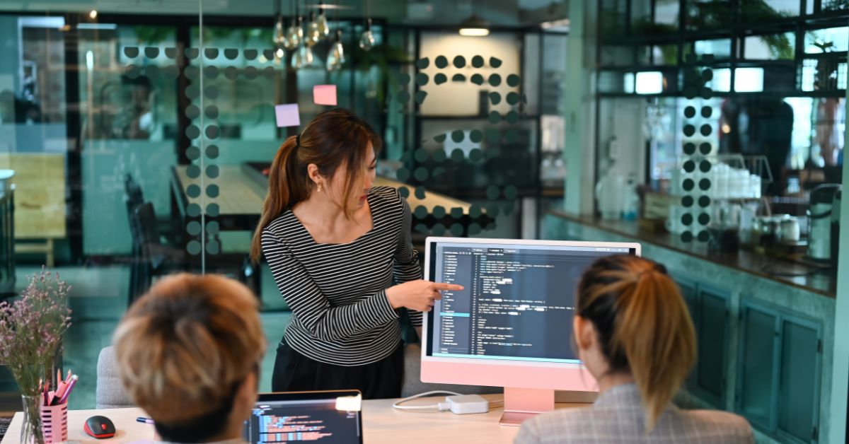 Diseñadora web presentando una idea de software a dos colegas trabajadoras, en una oficina muy moderna