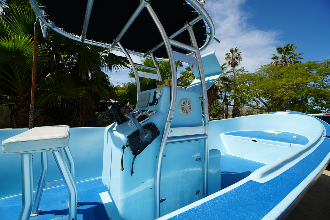 The open deck, helm and T-top of a freshly finished blue panga viewed from the bow quarter.