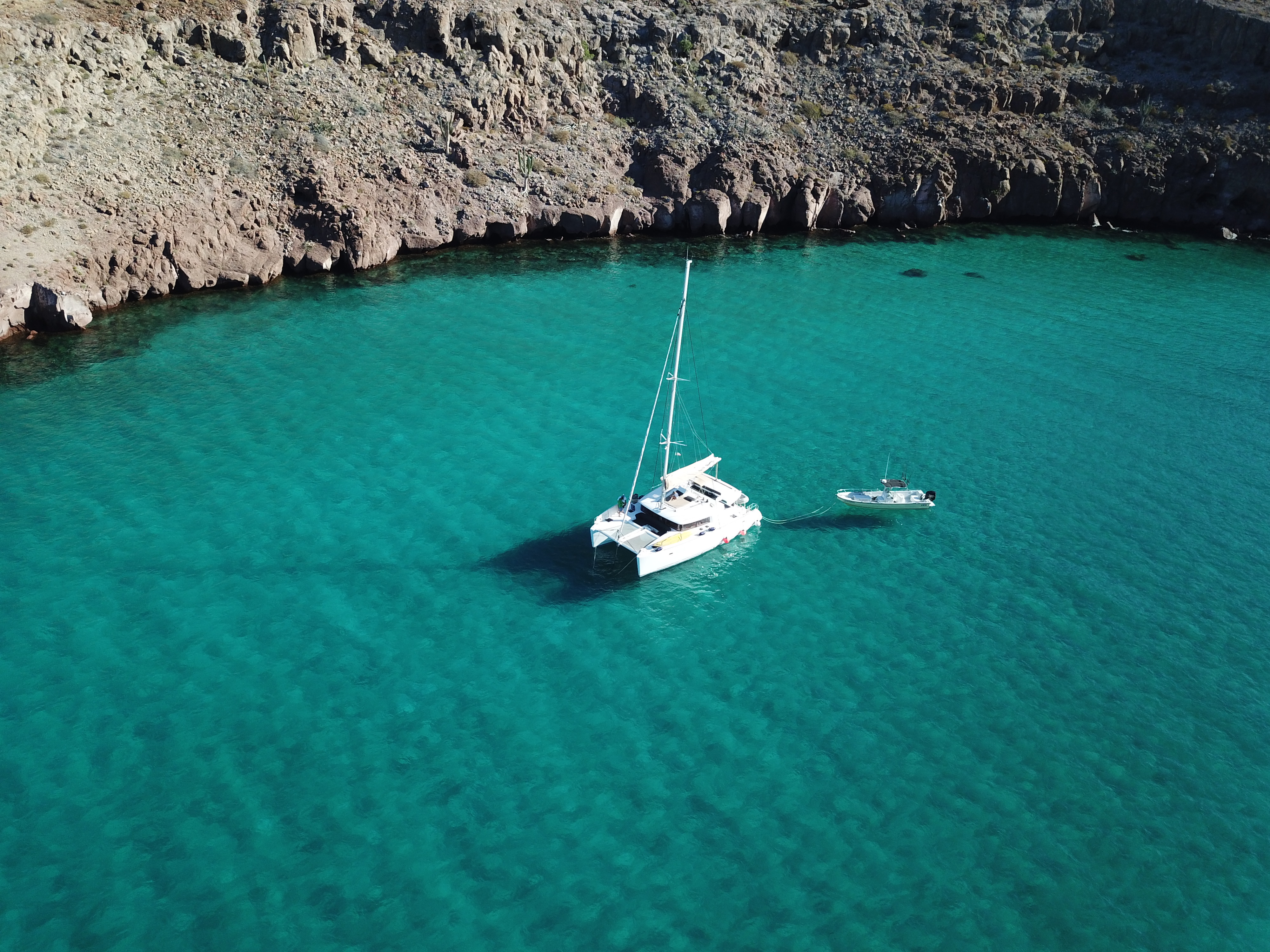 Aerial view of a catamaran anchored in a clear Baja cove