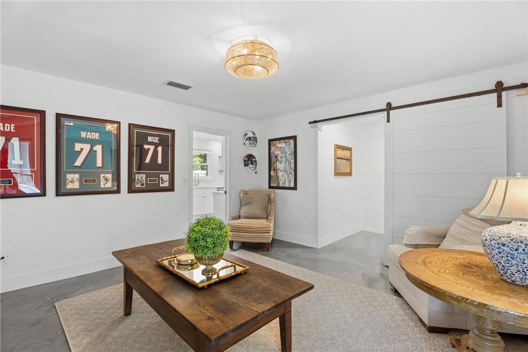 Interior space featuring a white sliding barn door, horizontal shiplap wall detailing, polished concrete flooring, and a circular drum flush-mount light fixture