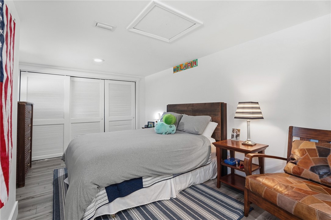 Room featuring wood-finish flooring, recessed lighting, and a closet with multi-panel louvered doors