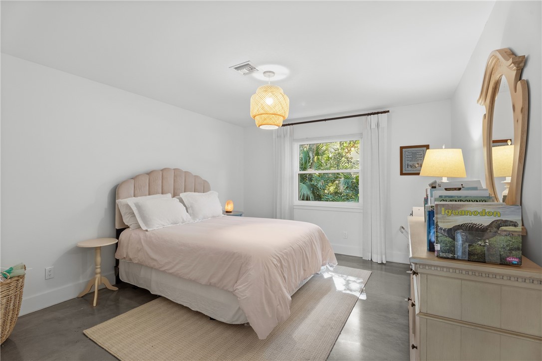 Interior room featuring smooth-finish flooring, a neutral color palette, a central woven pendant light fixture, and a single-pane window with custom drapery