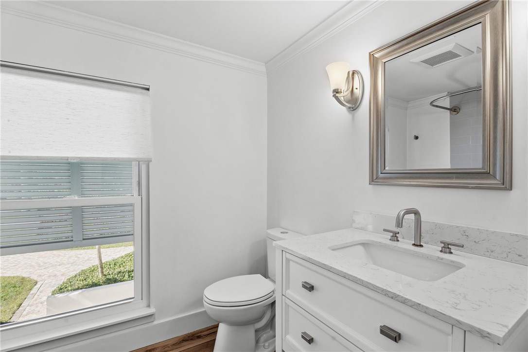 Bathroom featuring a white vanity with a stone-top integrated sink, chrome widespread faucet, wall-mounted light fixture, and framed vanity mirror