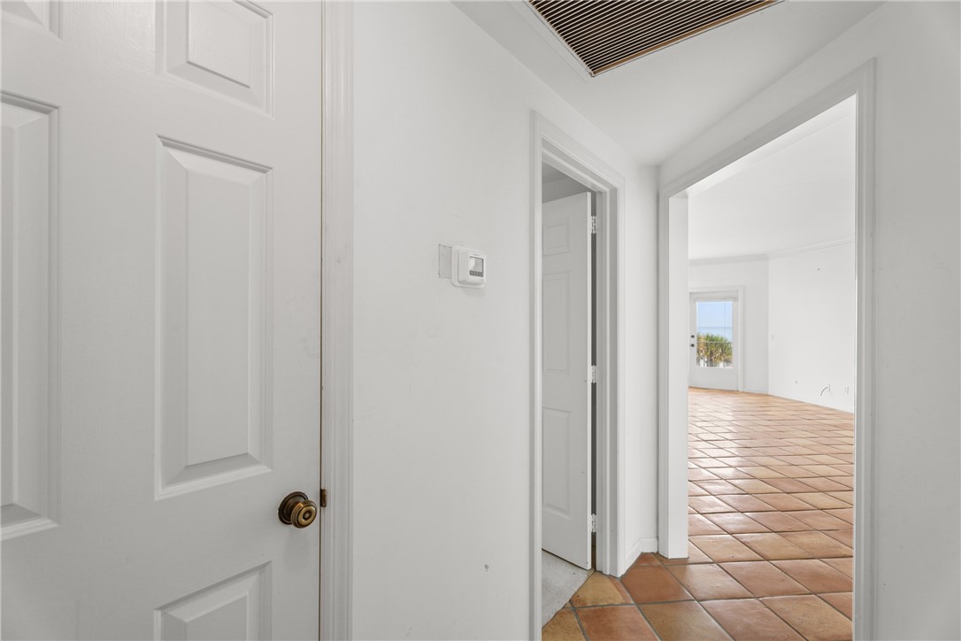 Interior hallway featuring white walls and terracotta tile flooring