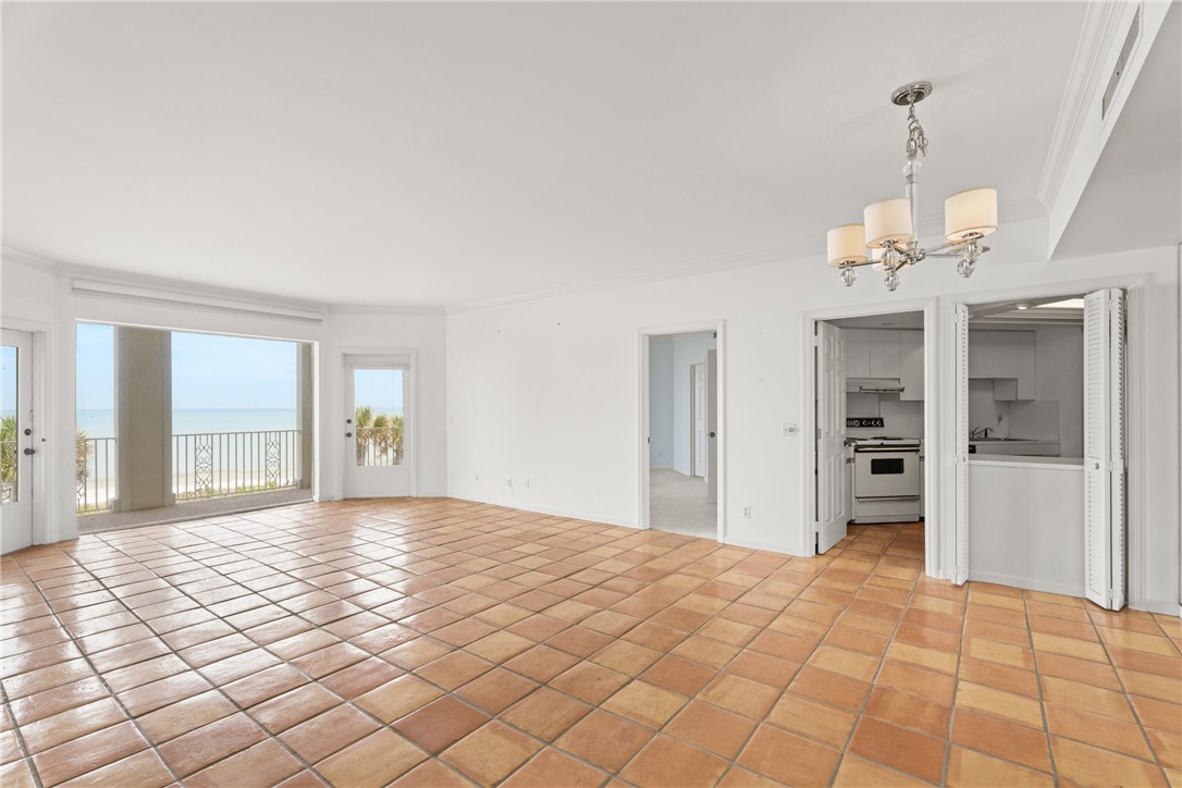 Expansive interior featuring terracotta-style tile flooring, white walls, and a decorative chandelier