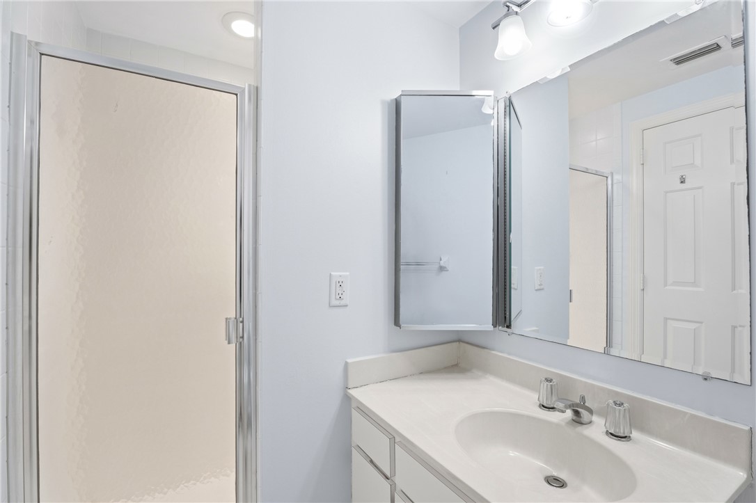 Bathroom vanity with a white countertop and integrated sink, chrome faucet, medicine cabinet, and a large wall mirror
