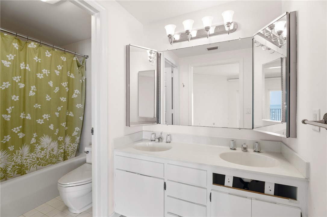 Bathroom featuring a double vanity with white cabinetry, integrated sinks, and a light-toned countertop