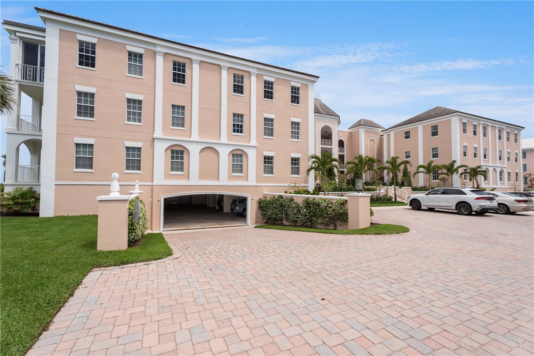 Multi-story building featuring a pale pink stucco exterior with white trim and multiple windows