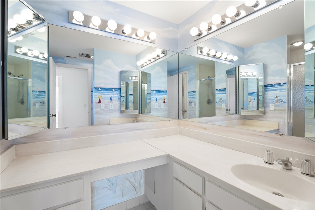 Spacious bathroom vanity featuring an integrated sink, ample countertop space, and extensive mirrored walls